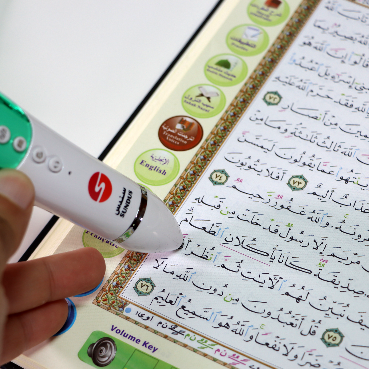 Sundus Quran reading pen touching a genuine colour-coded Uthmani Quran page, with printed audio controls